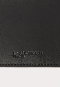 Μαύρο δερμάτινο πορτοφόλι με ανάγλυφο λογότυπο "KARL LAGERFELD JEANS". Υφή επιφάνειας με λείο περίγραμμα και διακριτική κοπή ρα�φής.