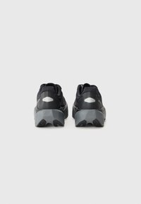 Chaussures de sport noires avec une tige en maille texturée, un col rembourré et des semelles en caoutchouc gris. Détails réfléchissants sur le talon pour une meilleure visibilité.