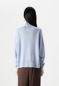 Jasnoniebieski, oversize sweter z półgolfem, szerokimi rękawami i prążkowanym dołem. Miękki w dotyku, z lekko luźnym krojem, zaprojektowany z myślą o komforcie.