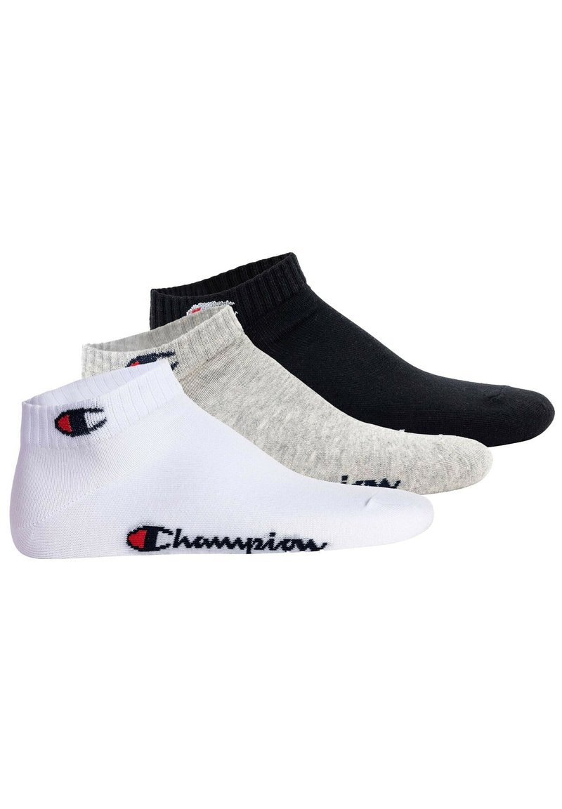 Tre par ankelsockor i vitt, grått och svart, med ribbade manschetter och en logotypsaccent som visar "Champions" i kontrasterande färger.