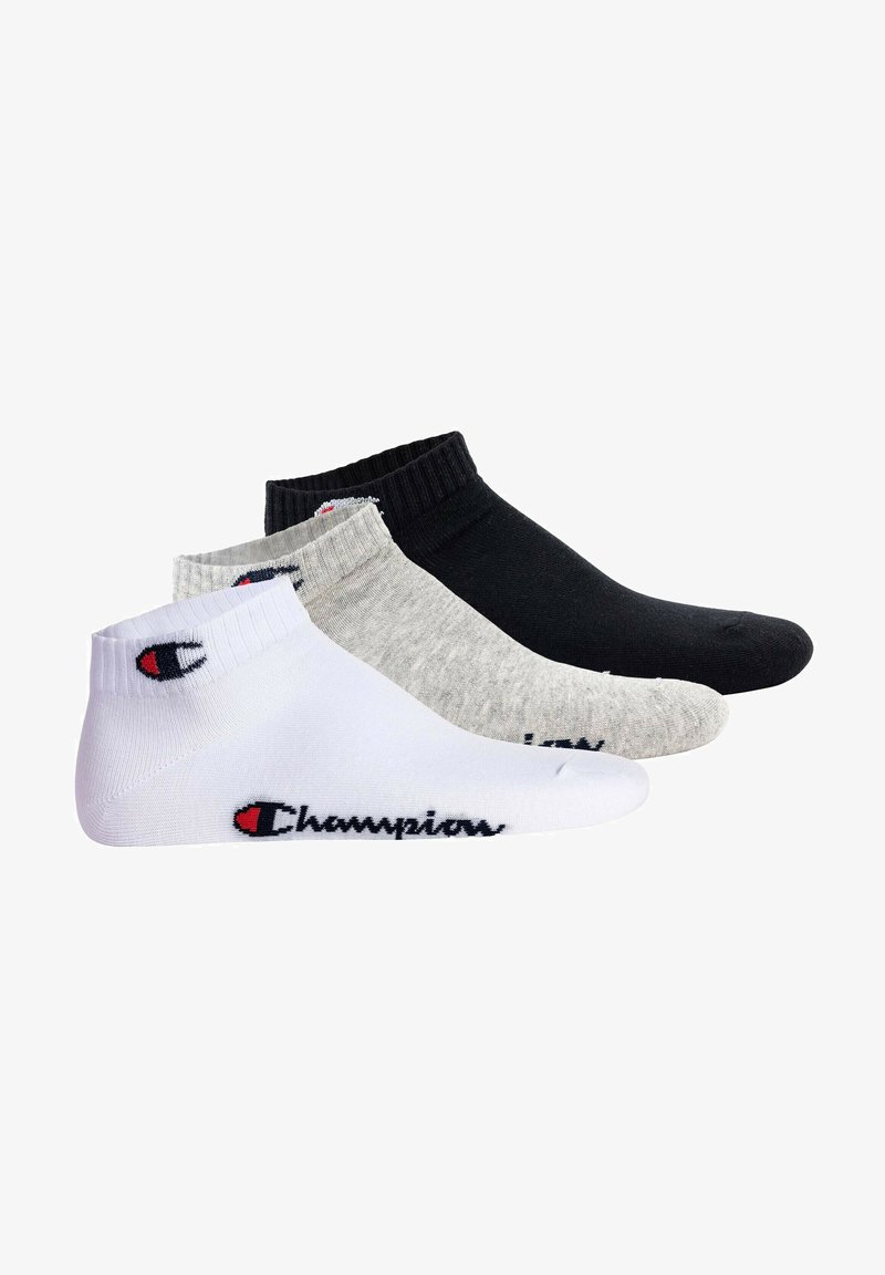 Tre paia di calzini alla caviglia in bianco, grigio e nero, con polsini a coste e un accento con logo che mostra "Champions" in colori a contrasto.