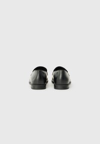 Zapatos de cuero negro con un acabado suave, suelas planas y forma redondeada, con costuras mínimas y un diseño clásico.