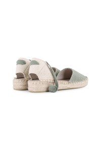 Zapatos de espadrilles con parte superior tejida en verde pálido, lados abiertos y suela de yute natural. Detalle decorativo de lazada enrollada en el talón.