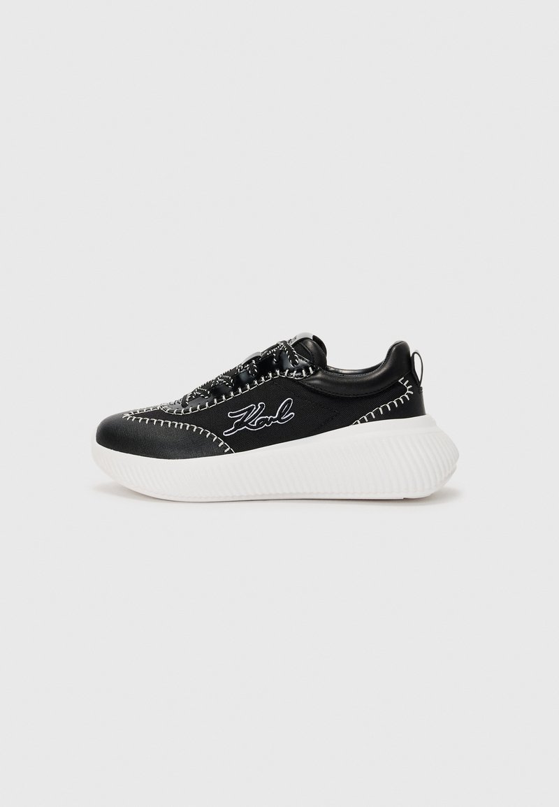 Basket noire avec semelle blanche, fabriquée en cuir et tissu. Présente des coutures contrastées et un logo sur le côté. Talon légèrement rehaussé.