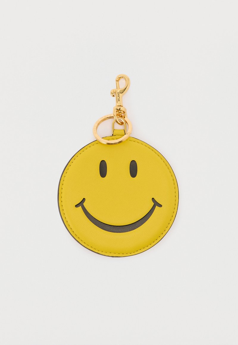 Κίτρινο στρογγυλό μπρελόκ με μαύρο χαμογελαστό πρόσωπο και χρυσό μεταλλικό κλιπ και κρίκο κλειδιών σε λευκό φόντο.