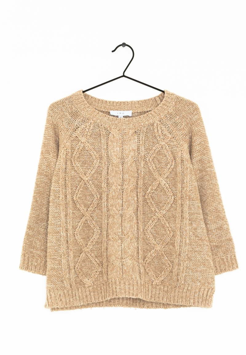 Beige stickad tröja med rund halsringning, med ett texturerat diamantmönster i kabelstickning och långa ärmar, hängande på en svart krok.