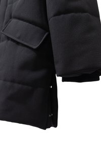 Zwarte gewatteerde jas met een gladde textuur, voorzien van een zijspleet en een zak aan de voorkant, benadrukt door ribbelmanchetten.