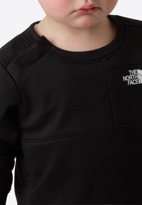 Felpa nera con collo rotondo e maniche lunghe, con logo del marchio bianco e design a pannelli a contrasto sul davanti.