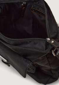 Zwarte stoffen tas met een open rits die een ruime binnenkant onthult. Voorzien van een ritszak en contrasterende bruin lederen accenten.