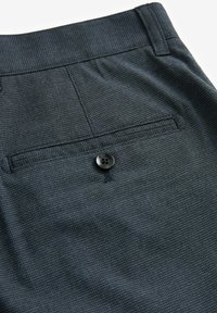 Donkere, gemusterde broek van een gestructureerde stof, met een enkele achterzak, een zwarte knoopsluiting en een gestructureerde tailleband.