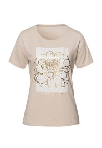 Beżowa koszulka z miękkiej bawełny, z białą prostokątną grafiką z złotą obwódką w kształcie kwiatu oraz tekstem poniżej. Krótkie rękawy.