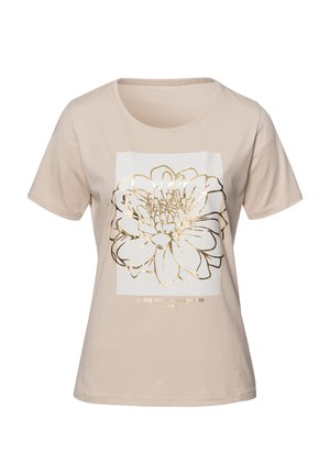 Beżowa koszulka z miękkiej bawełny, z białą prostokątną grafiką z złotą obwódką w kształcie kwiatu oraz tekstem poniżej. Krótkie rękawy.