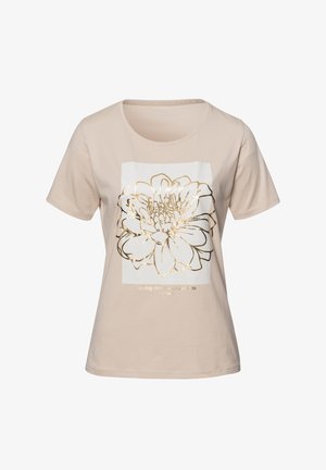 Beżowa koszulka z miękkiej bawełny, z białą prostokątną grafiką z złotą obwódką w kształcie kwiatu oraz tekstem poniżej. Krótkie rękawy.