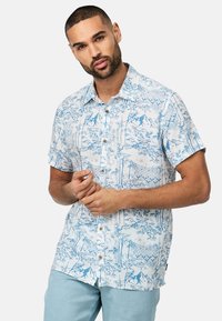 Camisa de botón de manga corta en azul claro con fondo blanco. Presenta un estampado de naturaleza detallado y botones de madera.