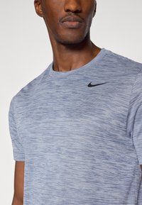 Κοντομάνικη μπλούζα Nike σε ανοιχτό γαλάζιο μέτριο χρώμα, με στρογγυλή λαιμόκοψη, υφασμάτινη υφή και μαύρο λογότυπο στο στήθος.