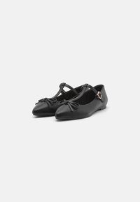Bailarinas de cuero negro con punta afilada, correa ajustable y lazos decorativos en la parte delantera. Textura suave y diseño minimalista.