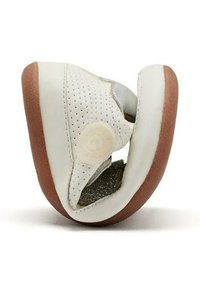 Zapato de escalada blanco con parte superior de cuero perforado, acentos grises y suela de goma marrón. Presenta un distintivo logo en espiral en el lateral.