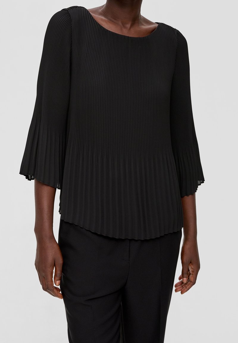 Svart plisserad topp med rund halsringning och trekvartsflared ärmar, med en mjuk textur och flödande silhuett.
