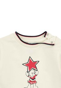Naturfarbenes T-Shirt mit Rundhalsausschnitt, das ein Bärenmotiv zeigt, der einen roten Stern hält, sowie einen gestreiften Akzent in Rot und Schwarz am Kragen.