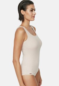 Débardeur beige clair, fabriqué en tissu extensible, avec un décolleté dégagé, des fines bretelles et des côtés sans coutures pour un ajustement lisse.