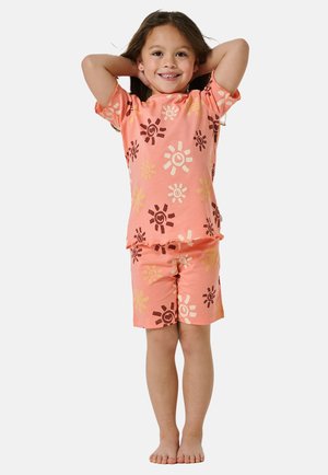 To-delt børnertøj i lys koral, med korte ærmer og shorts. Dekoreret med blomster mønstre i brun og gul.
