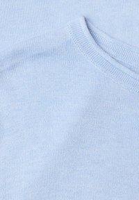 Tissu tricoté bleu clair avec un col rond côtelé, montrant un gros plan du détail de la texture et des coutures du pull.
