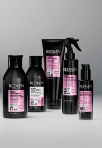 Five Redken hair care products with pink labels for acidic color gloss and naked gloss, arranged in a row on a gray background.