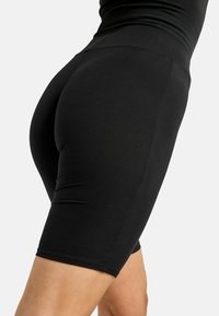 Schwarze, hochtaillierte Radlerhosen aus elastischem Stoff, mit glatter Oberfläche und einer Länge bis zur Mitte des Oberschenkels, ausgestattet mit minimalen Nähten.