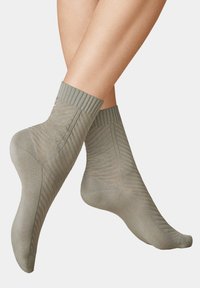Kurze Socken in hellgrün, mit geripptem Bund, strukturiertem Design und glattem Körper, die schlanke Linien und subtile Details betonen.