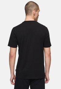 Svart bomullströja med korta ärmar, rundad halsringning och rak nederkant. Har en liten etikett på vänster baksida.