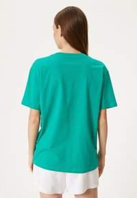 Turkis kortærmet t-shirt med rund hals, lavet af blødt bomuldsstof, med et ensfarvet design uden synlige mønstre.