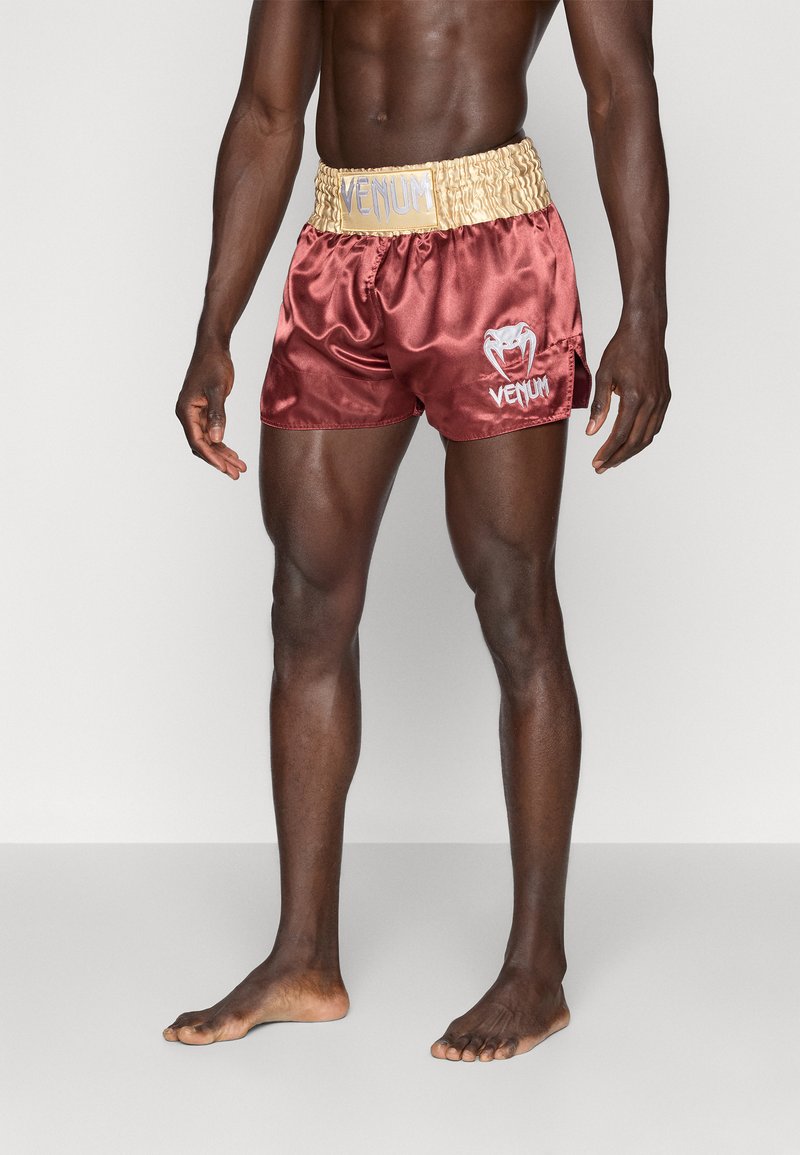 Shorts de boxeo de satén burdeos con una cinturilla elástica texturizada en dorado; presenta la marca y el logo de VENUM en blanco en el lado izquierdo.