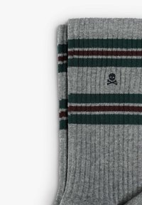 Calcetines de rayas grises con verde y burdeos y un pequeño logo de calavera en la parte superior. Hechos de un material tejido suave.