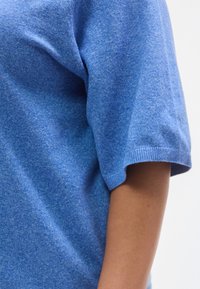 Μπλε πουκάμισο με κοντά μανίκια από απαλό, υφασμένο ύφασμα με άνετη εφαρμογή. Διαθέτει μανσέτες με ριμπ ύφανση και διακριτικό ελαφ ρώς ψαθυρό σχέδιο.