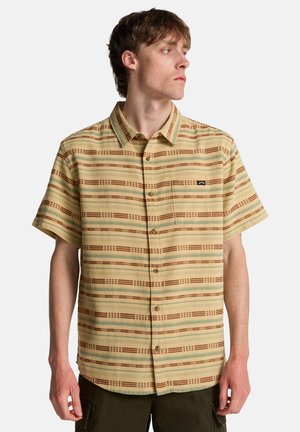 Camicia a maniche corte con bottoni in giallo chiaro, caratterizzata da un motivo a righe con accenti marroni e verdi, e una tasca sul petto.