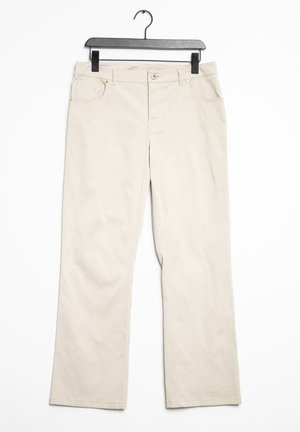 Pantalons en coton beige avec une coupe droite, dotés de quincaillerie dorée et de deux poches avant, suspendus sur un cintre noir.