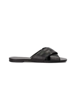 Black leather slide sandal featuring a crisscross strap design, flat sole, and a smooth texture. Simple and minimalistic style.
