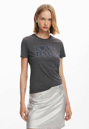 Camiseta de algodón gris con escote redondeado, que presenta "LOVE DSGL" en piedras brillantes azules. Combinada con una falda plateada brillante.