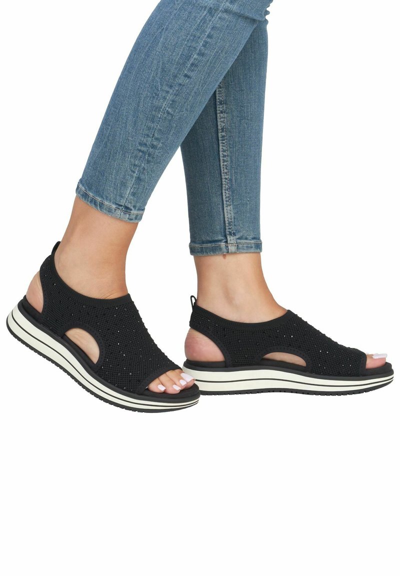 Zwarte sandalen met een gebreide bovenkant met uitsnijdingen, een dikke witte tussenzool en een gestructureerde zwarte buitenzool voor grip.