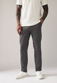 Gray cotton trousers with a slim fit, complemented by a textured white shirt and white sneakers. Features include a classic design and subtle detailing.