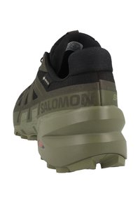 Scarpa da trail running Salomon caratterizzata da una colorazione nera e oliva, parte superiore in Gore-Tex testurizzato, suola ammortizzata e dettagli del logo ben visibili.
