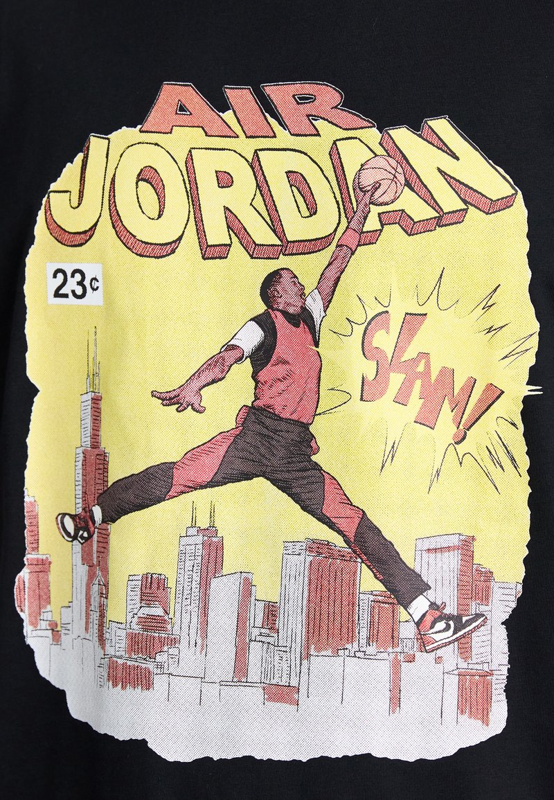 Schwarzes T-Shirt mit einem Grafikmotiv eines springenden Basketballspielers in rotem und weißem Trikot, auf gelbem Hintergrund mit Stadtsilhouette.