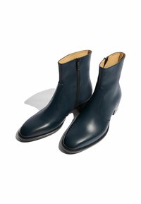 Botines de piel azul marino con punta afilada, cremallera lateral y textura suave. Presenta un tacón bajo y sutilezas en la costura.