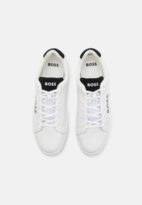 Sneaker in pelle bianca con dettagli neri, punta rotonda, lacci bianchi piatti e logo "BOSS" sul lato e sulla linguetta. Fodera interna textured.
