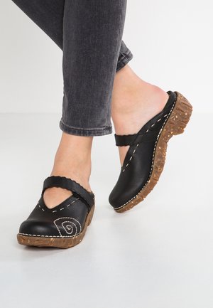 Black leather clogs with a cutout design, featuring a scalloped strap and beige stitching. Rubber sole with textured detailing, elevated heel.