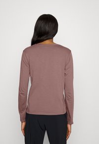 Långärmad skjorta i dämpad mauve, med rund hals och slät textur, rak nederkant och minimalistisk design.