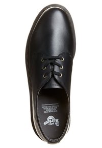 Scarpa nera in pelle di Dr. Martens con lacci, punta arrotondata, cuciture gialle visibili sulla suola e testo del marchio sulla soletta.