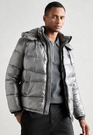 Chaqueta gris metálica acolchada con capucha, cierre frontal con cremallera y bolsillos laterales. Presenta un patrón acolchado y puños elásticos para un ajuste ceñido.