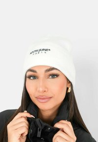 Vit stickad mössa med texten "SIXTH JUNE PARIS" i svart broderi. Mjuk textur, vikbar muddgummi och minimalistisk design.