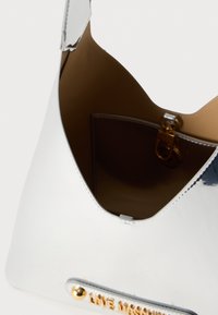 Ασημένια μεταλλική τσάντα με ομαλή υφή, τριγωνικό σχήμα, καφέ δερμάτινη επένδυση και χρυσές μεταλλικές λεπτομέρειες στη βάση.